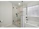 Modern bathroom featuring a glass shower with a black handle, a tiled wall and window, and a bathtub at 13032 Windy Lea Ln, Huntersville, NC 28078