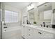 Bright bathroom featuring a white vanity with double sinks, a tiled wall, framed mirrors, and a bathtub at 13032 Windy Lea Ln, Huntersville, NC 28078