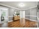 Open living room with hardwood floors, gray walls, white trim, and a modern console table beneath a round mirror at 13032 Windy Lea Ln, Huntersville, NC 28078