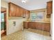 Spacious kitchen area features wood cabinets, a window over the sink, and vintage-style flooring at 1513 Shelby Hwy, Cherryville, NC 28021