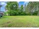 Large, well-maintained backyard featuring a spacious grassy area with mature trees and landscaping at 15637 Guthrie Dr, Huntersville, NC 28078