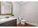 Charming powder room with a rustic-style mirror, shiplap accent wall, and dark wood flooring at 15637 Guthrie Dr, Huntersville, NC 28078