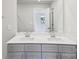 Bathroom with double vanity sinks, gray cabinets, large mirror, and view into an adjacent bedroom at 1712 Braemar Village Dr, Monroe, NC 28110