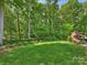 Beautiful, lush backyard with manicured lawn, wooded backdrop, and outdoor fireplace feature at 2129 Halford Pl, Charlotte, NC 28211
