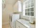 Well-lit laundry room featuring a modern washer and dryer, sink, granite countertops, and ample cabinet space at 2129 Halford Pl, Charlotte, NC 28211