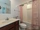 Bright bathroom featuring a vanity, toilet, shower-tub combo, and stylish pink shower curtains at 2715 Sydney Overlook Ln, Charlotte, NC 28269