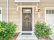 A welcoming front door adorned with a floral wreath, complemented by neatly trimmed bushes and classic exterior details at 2715 Sydney Overlook Ln, Charlotte, NC 28269