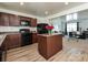 Well-lit kitchen with dark cabinets, black appliances, an island, and an open view to the living room at 2715 Sydney Overlook Ln, Charlotte, NC 28269