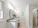 Bright bathroom featuring double vanity with framed mirrors, stone countertop and wood floor at 300 Hugh Crocker Rd, Matthews, NC 28104