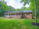 Inviting brick ranch with a classic covered porch, surrounded by a beautifully maintained lawn and natural landscaping at 300 Hugh Crocker Rd, Matthews, NC 28104