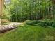 Beautifully landscaped backyard with a stone patio, lush lawn, and mature trees, creating a serene retreat at 3825 Mountain Cove Dr, Charlotte, NC 28216