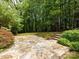 A backyard features a stone patio and mature landscaping, offering a peaceful and private outdoor space at 3825 Mountain Cove Dr, Charlotte, NC 28216