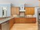 This kitchen has wooden cabinets, a stainless steel fridge, granite counters, a tile backsplash, and a wood floor at 3825 Mountain Cove Dr, Charlotte, NC 28216
