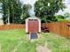View of a backyard shed, lawn mower, and wooden fence, set on a green lawn and enclosed by lush trees at 4698 Hannah Dr, Rock Hill, SC 29732