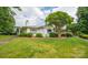 Charming single-story home with beautifully manicured lawn, lush shrubbery, and mature shade tree at 5833 Harris Grove Ln, Charlotte, NC 28212