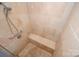 Walk-in shower featuring neutral stone-look tile walls, a shower bench, and a handheld shower head at 5833 Harris Grove Ln, Charlotte, NC 28212
