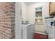 Practical laundry area with white appliances, a brick wall accent, and storage cabinet at 851 Gist Rd, Rock Hill, SC 29732