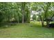 Large backyard with mature trees, seating, a trampoline, a storage structure and a covered car parking area at 857 Hills Rd, Belmont, NC 28012