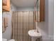 Compact bathroom featuring a pedestal sink, and a shower with plaid shower curtain at 857 Hills Rd, Belmont, NC 28012