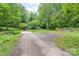 A long driveway leading to a house with ample parking, a shed, an American flag, and trees around it at 857 Hills Rd, Belmont, NC 28012