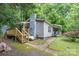 Side view of a cozy home featuring a chimney, wooden stairs, mature trees and vibrant landscaping at 857 Hills Rd, Belmont, NC 28012