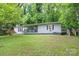 Charming ranch home featuring a cozy porch, a small set of stairs, surrounded by lush greenery and a well-maintained lawn at 857 Hills Rd, Belmont, NC 28012