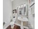 Stylish half bathroom with pedestal sink, decorative mirror, and wood flooring at 9075 Blue Ridge Dr, Indian Land, SC 29707