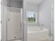 Bright bathroom featuring a glass shower, a soaking tub, and a window with natural light at 908 Sundance Dr, Gastonia, NC 28054
