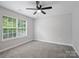 Bedroom boasts gray walls, plush carpet, a modern ceiling fan, and natural light at 908 Sundance Dr, Gastonia, NC 28054