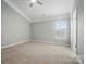 Spacious bedroom with plush carpeting, neutral walls, ceiling fan, and a window, offering a serene living space at 9711 Castle Terrace Ct, Charlotte, NC 28215