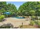 A stone patio leads to an in-ground pool surrounded by lush greenery at 1031 Butterburr Dr, Matthews, NC 28104