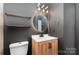 Contemporary bathroom showcases vanity with round mirror, unique sconces, and dark accent wall for a modern touch at 11109 Amur Ct, Charlotte, NC 28262