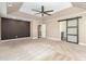 Large primary bedroom with dark accent wall, tray ceiling, ceiling fan, and barn door leading to bathroom at 11109 Amur Ct, Charlotte, NC 28262