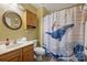 Unique bathroom showcasing a single vanity, round mirror, and shower with whimsical whale and cat curtain at 1117 Yarrow St, Matthews, NC 28104