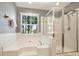 Bright bathroom featuring a corner soaking tub, walk-in shower, and a large window offering natural light at 1117 Yarrow St, Matthews, NC 28104