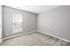 A well-lit empty bedroom features neutral paint, a window with blinds, and plush carpeting at 1117 Yarrow St, Matthews, NC 28104