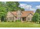 Charming brick home featuring a manicured lawn, complemented by lush greenery and mature trees at 1117 Yarrow St, Matthews, NC 28104