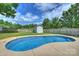 Sparkling in-ground pool surrounded by lush green grass, privacy fence, and a convenient storage shed at 1117 Yarrow St, Matthews, NC 28104