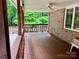 The back porch has dark wood floors and is surrounded by lush green trees at 1623 Arbor Way, Albemarle, NC 28001