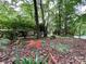 A tranquil front yard features tall trees, ground cover, flowers, and a glimpse of the home's brick exterior at 1623 Arbor Way, Albemarle, NC 28001