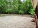 A spacious, empty concrete patio is adjacent to a wooden deck, offering outdoor living space surrounded by tall trees at 1623 Arbor Way, Albemarle, NC 28001