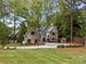 Charming stone home featuring a manicured lawn, mature trees, and a circular driveway at 19614 Meta Rd, Cornelius, NC 28031