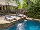 Relaxing pool area with lounge chairs, waterfall feature, and outdoor kitchen perfect for summer days at 19614 Meta Rd, Cornelius, NC 28031