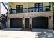 View of the garage with black doors, brick accents, and a second-story balcony above at 2925 Westfield Rd, Charlotte, NC 28209