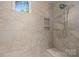 Close up of the walk-in shower featuring neutral tile, bench seat and shower head at 2925 Westfield Rd, Charlotte, NC 28209