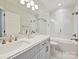 Bright bathroom featuring a white vanity, marble countertop, and a shower-tub combo with glass door at 4608 Morrowick Rd, Charlotte, NC 28226
