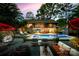 A beautiful outdoor pool lit up at dusk, surrounded by comfortable lounge seating on a wooden deck at 4609 Rounding Run Rd, Charlotte, NC 28277