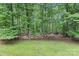 Grassy backyard with trees on a sunny day, and a view from the lawn into the tree line at 505 Kemp Rd, Mooresville, NC 28117