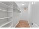 Well-organized walk-in closet with built-in shelving and wood floor at 505 Kemp Rd, Mooresville, NC 28117