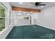 Open living room with exposed wood beams, large windows and green carpet at 505 Kemp Rd, Mooresville, NC 28117
